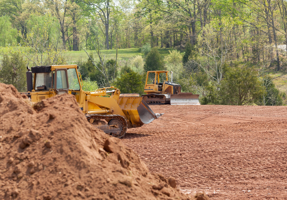 Land being levelled and cleared by yellow earth moving digger